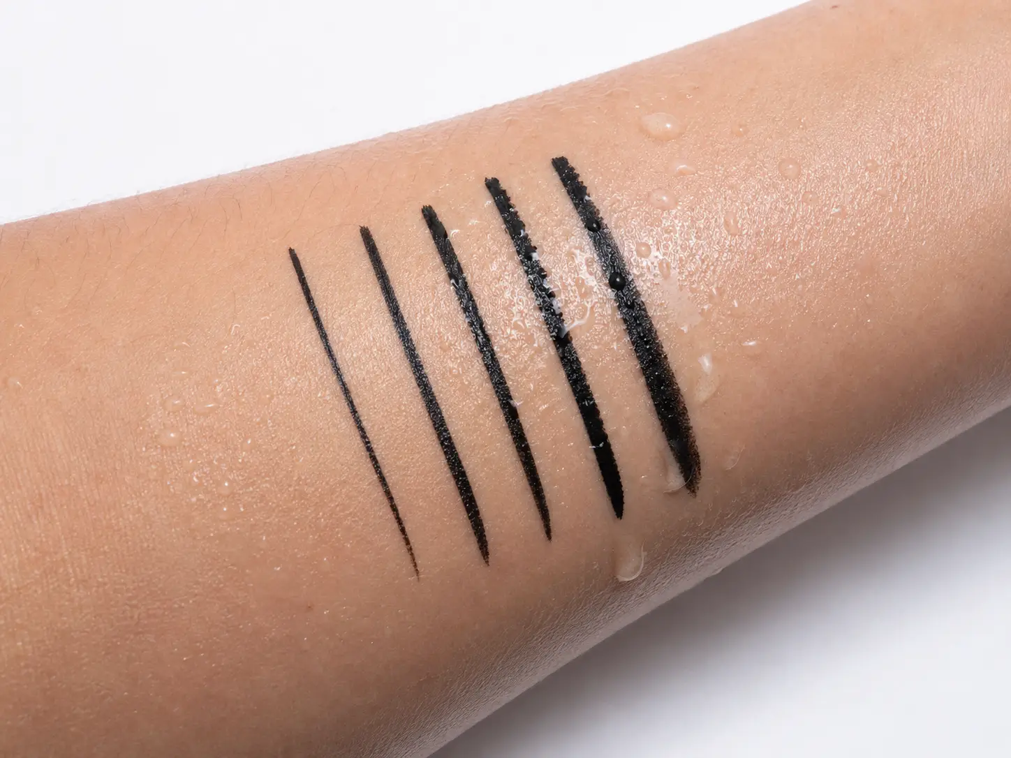 Waterproof eyeliner product on a clean vanity surface with water droplets